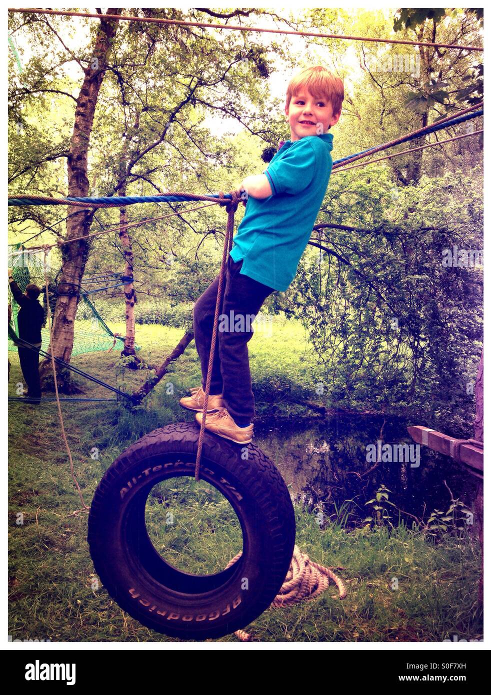 Boy swinging sur une corde et tire. Cours d'aventure. Parcours du combattant. Jeux forestiers Banque D'Images