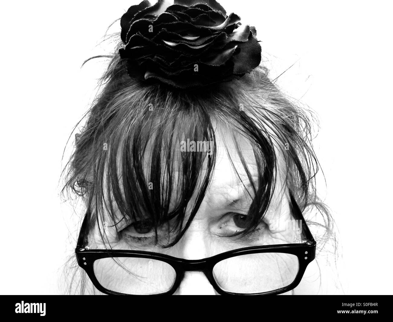 Vieillesse portant des lunettes de lecture et flower in her hair Banque D'Images