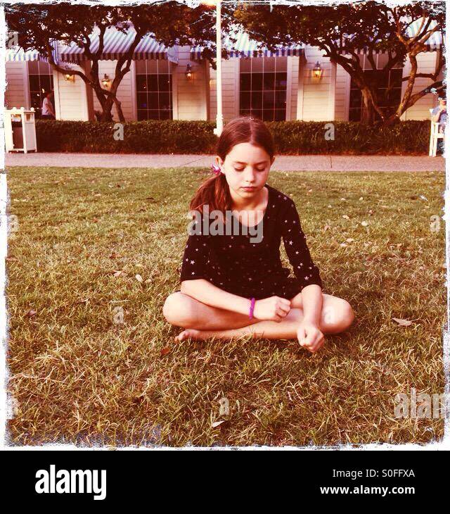 Girl sitting in grass cross legged - Image de stock capturée avec un smartphone