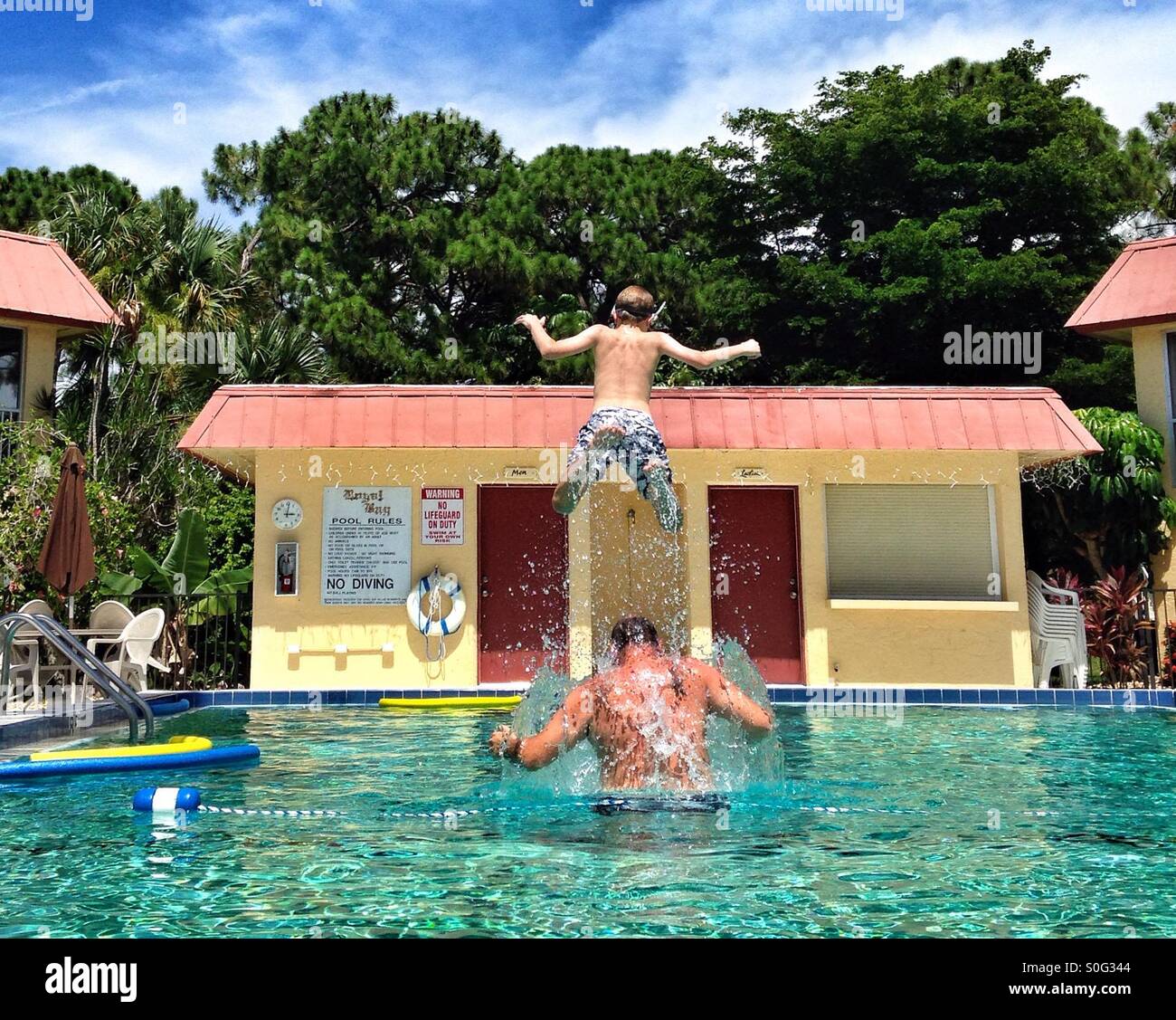 Sautant hors de l'enfant père épaules dans une piscine à Naples en Floride Banque D'Images