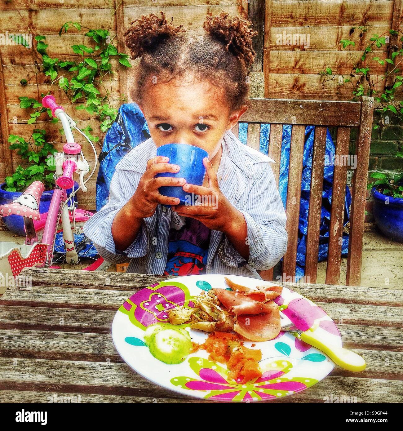 Un enfant a un repas dans le jardin. Banque D'Images