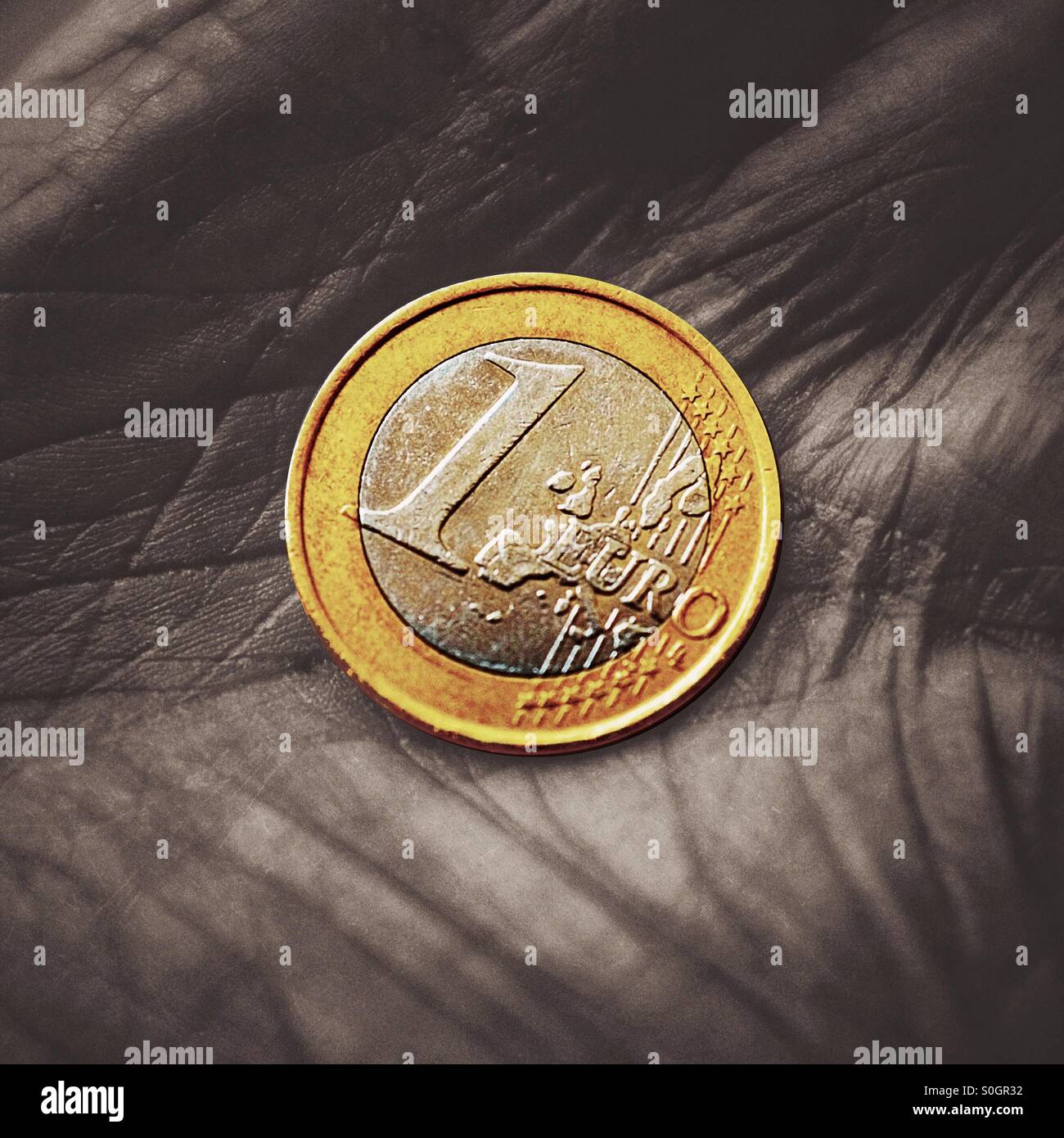 Un gros plan d'une pièce de un euro dans la main d'un retraité - Image de stock capturée avec un smartphone