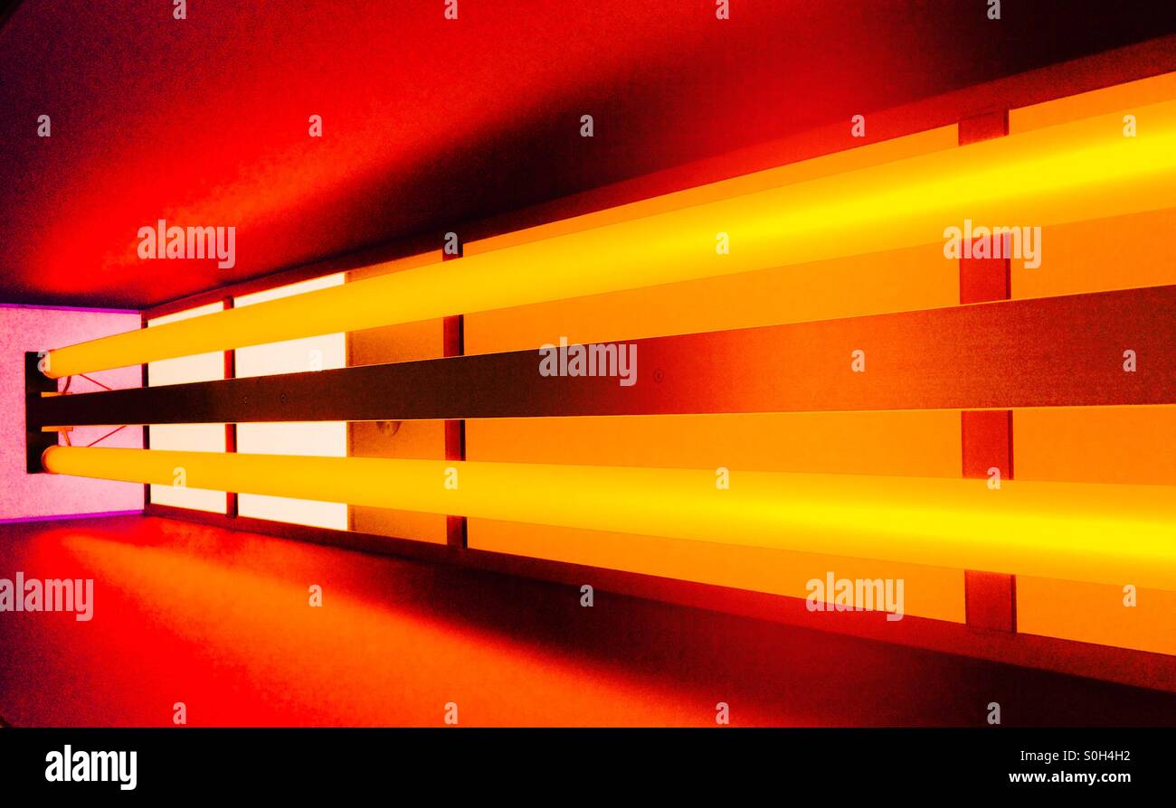Tubes fluorescents incased en perspex, omettant la lumière orange. Banque D'Images