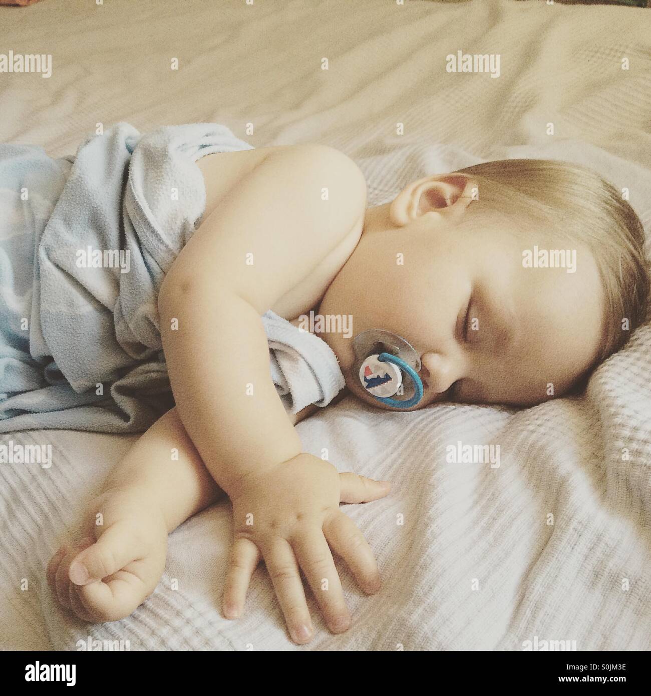 8 Mois Bebe Garcon Dormir Paisiblement Sur Une Chaude Journee D Ete Sur Le Lit Des Parents Recouvert D Une Couverture Bleu Clair Avec Une Sucette Dans Sa Bouche Photo Stock Alamy