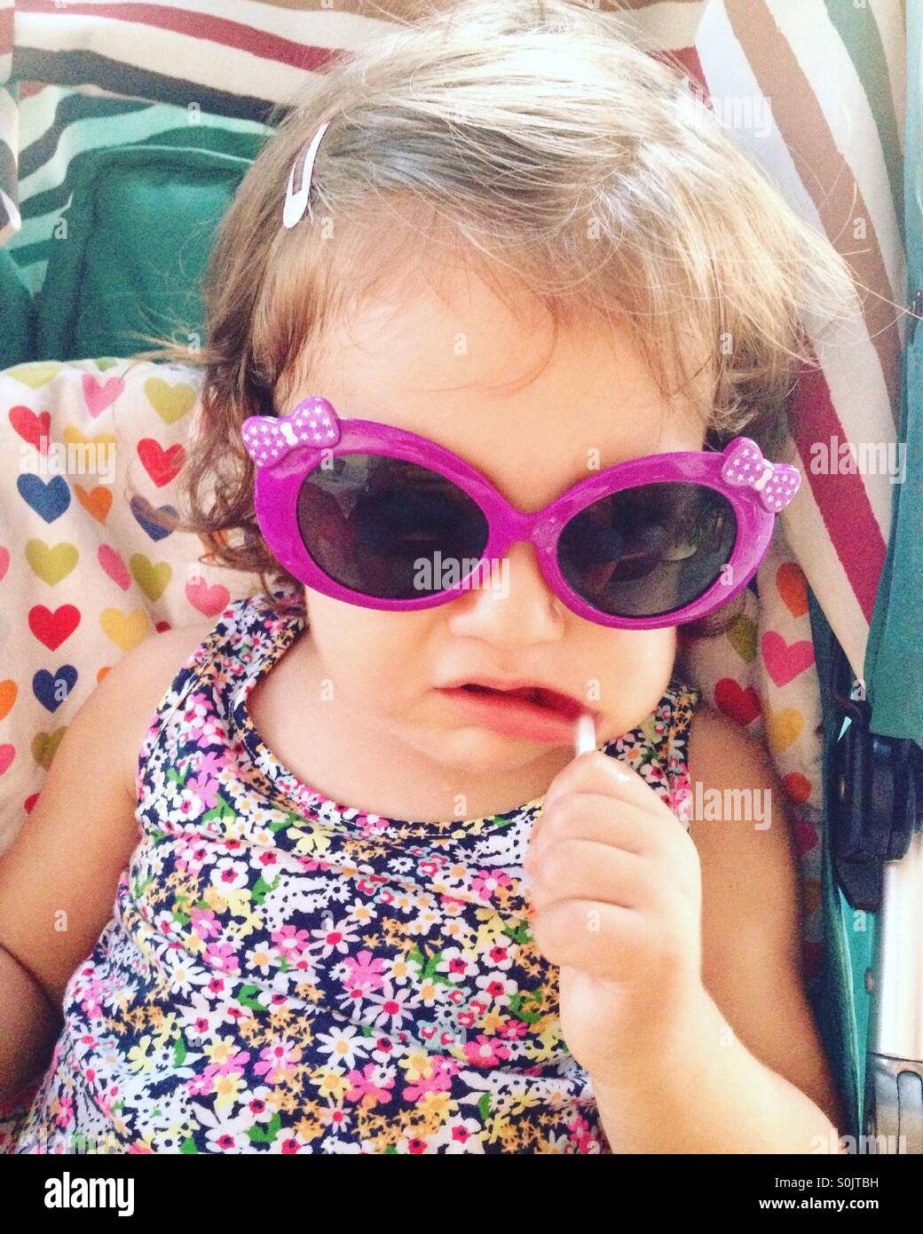 Baby Girl with lollipop et lunettes looking at camera Banque D'Images