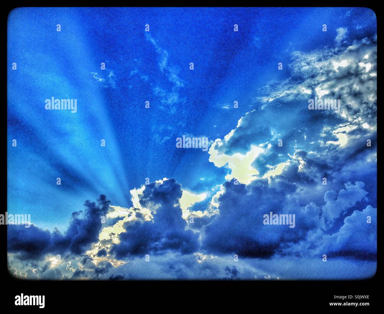 Les voisins musicaux de lumière à travers les nuages dans un ciel bleu. Crédit Photo - Colin Hoskins. - Image de stock capturée avec un smartphone