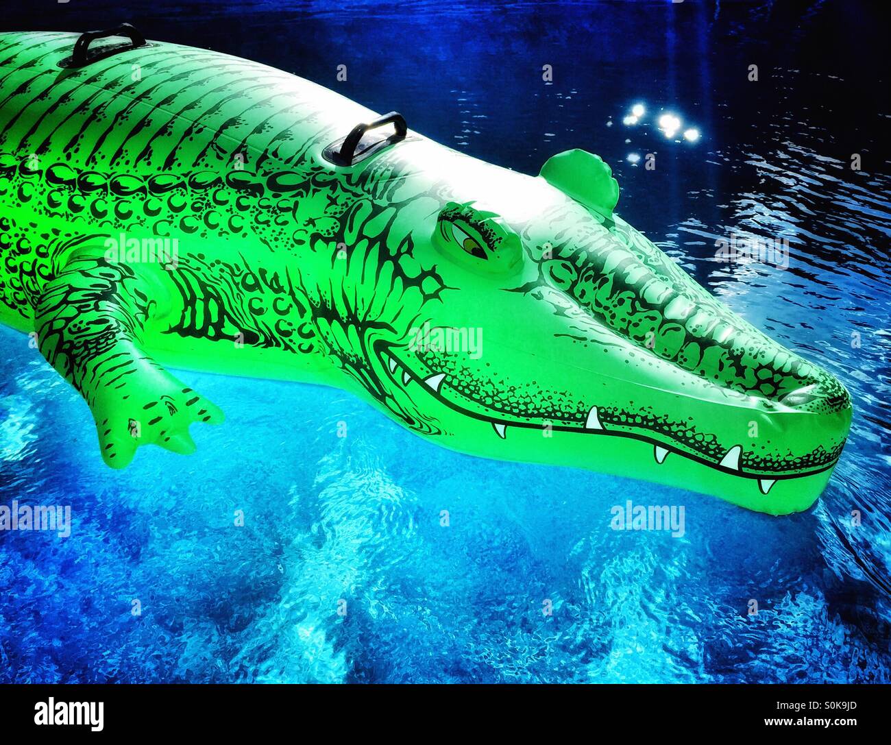 Alligator gonflable Jouet flottant sur l'eau bleue. Banque D'Images