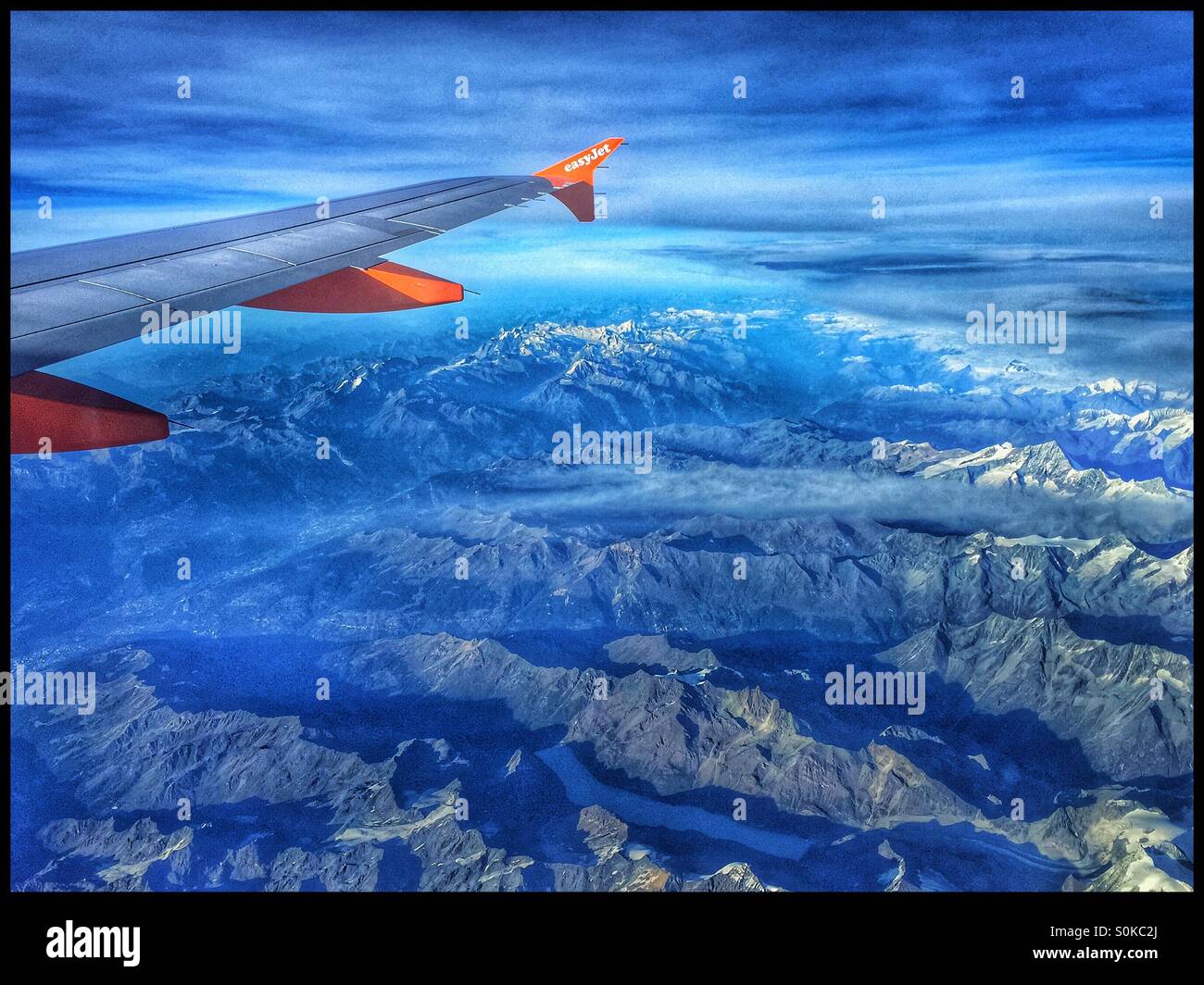 Vue d'une aile d'avion et les moteurs au-dessus de montagnes des Alpes, à partir d'un vol EasyJet au-dessus de la Suisse. Crédits photos - © COLIN HOSKINS. - Image de stock capturée avec un smartphone