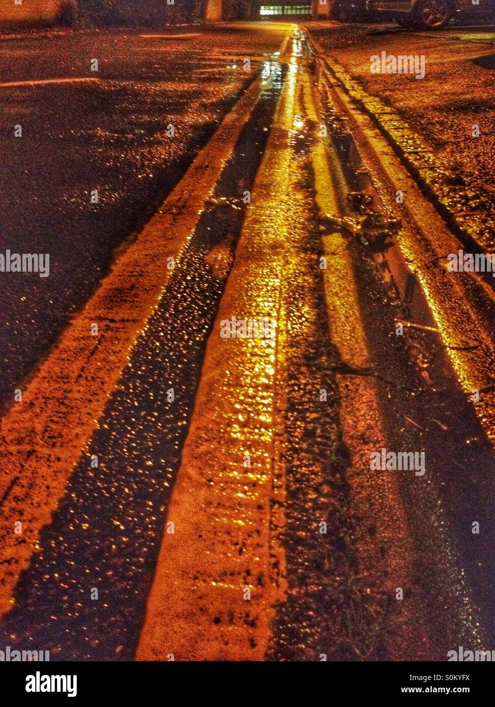 Les lignes jaunes double sur une nuit pluvieuse. - Image de stock capturée avec un smartphone