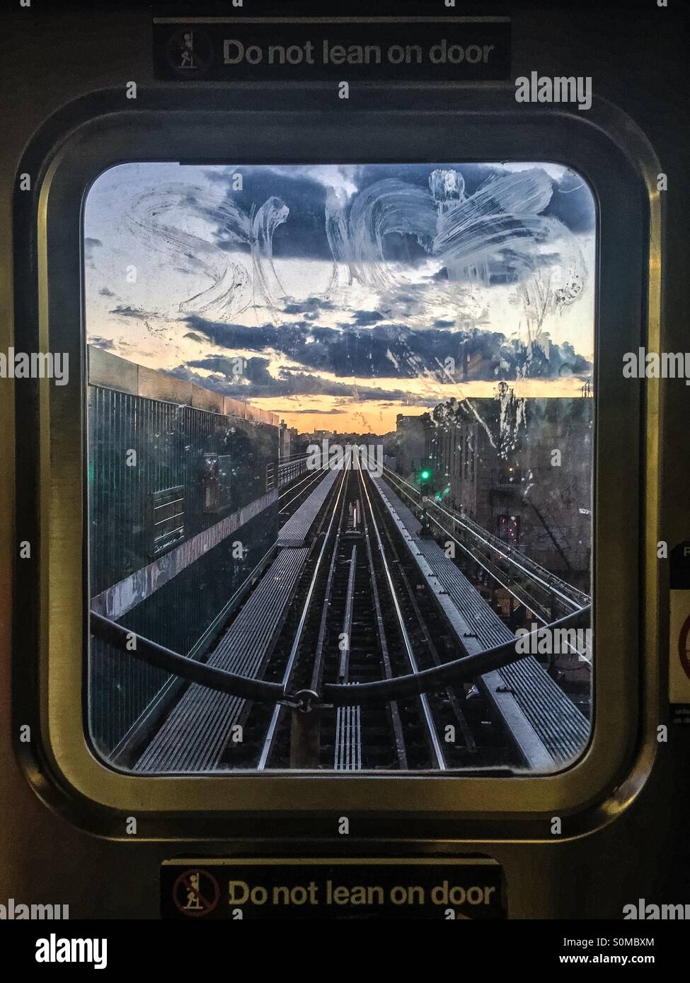 Vue sur le coucher de soleil à travers la fenêtre du métro train J dans la ville de New York. Banque D'Images