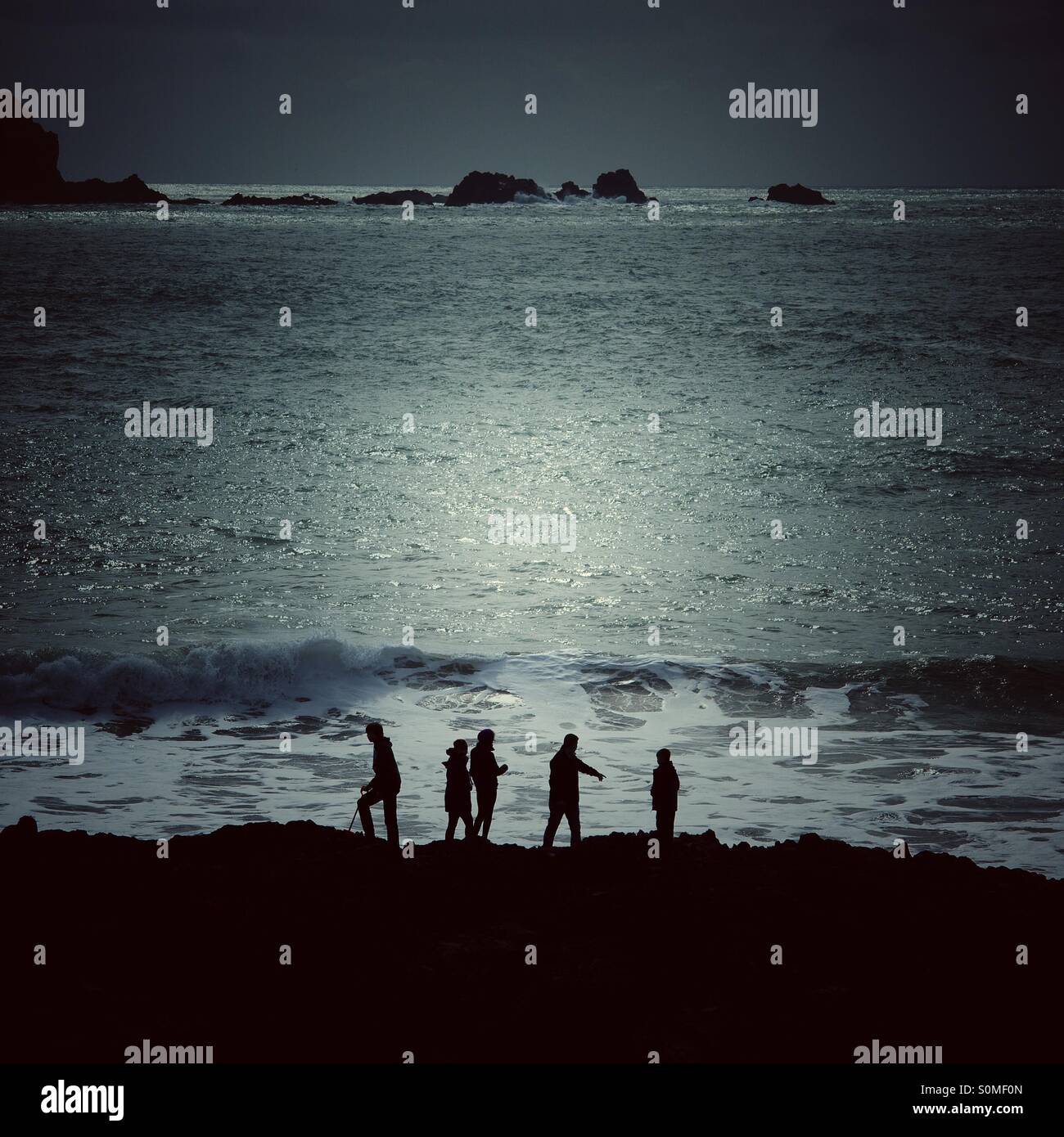 Cinq silhouettes sur une aventure à la mer. L'océan lune derrière eux. Banque D'Images