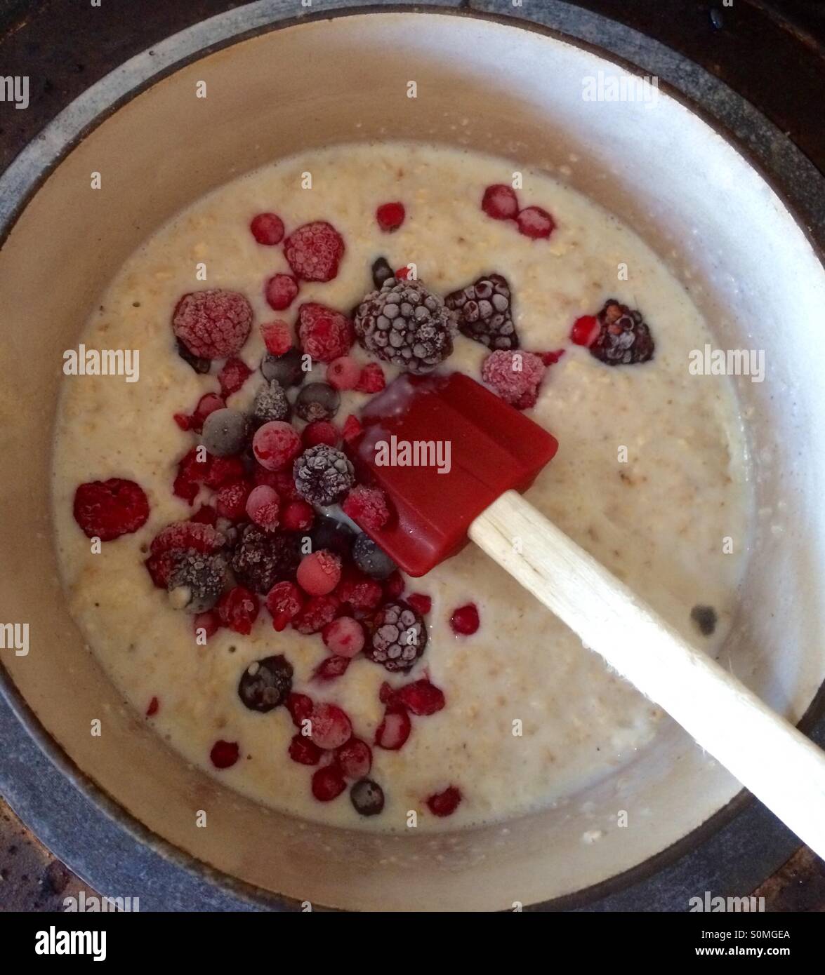 Petit-déjeuner d'automne - porridge avec des baies congelées ajouté lors de la cuisson Banque D'Images Petit-déjeuner d'automne - porridge avec des baies congelées ajouté lors de la cuisson Banque D'Images