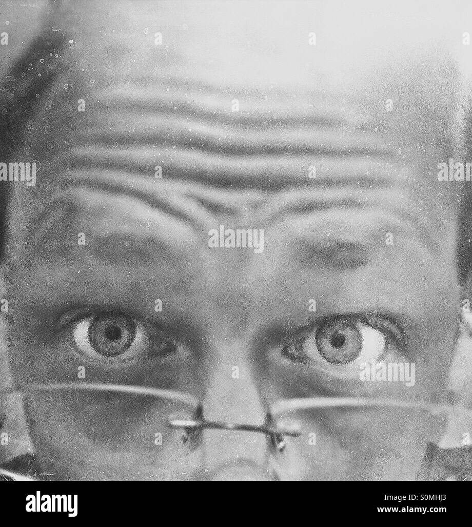 Portrait d'un homme haché à plus de ses lunettes avec des yeux perçants et front ridé Banque D'Images