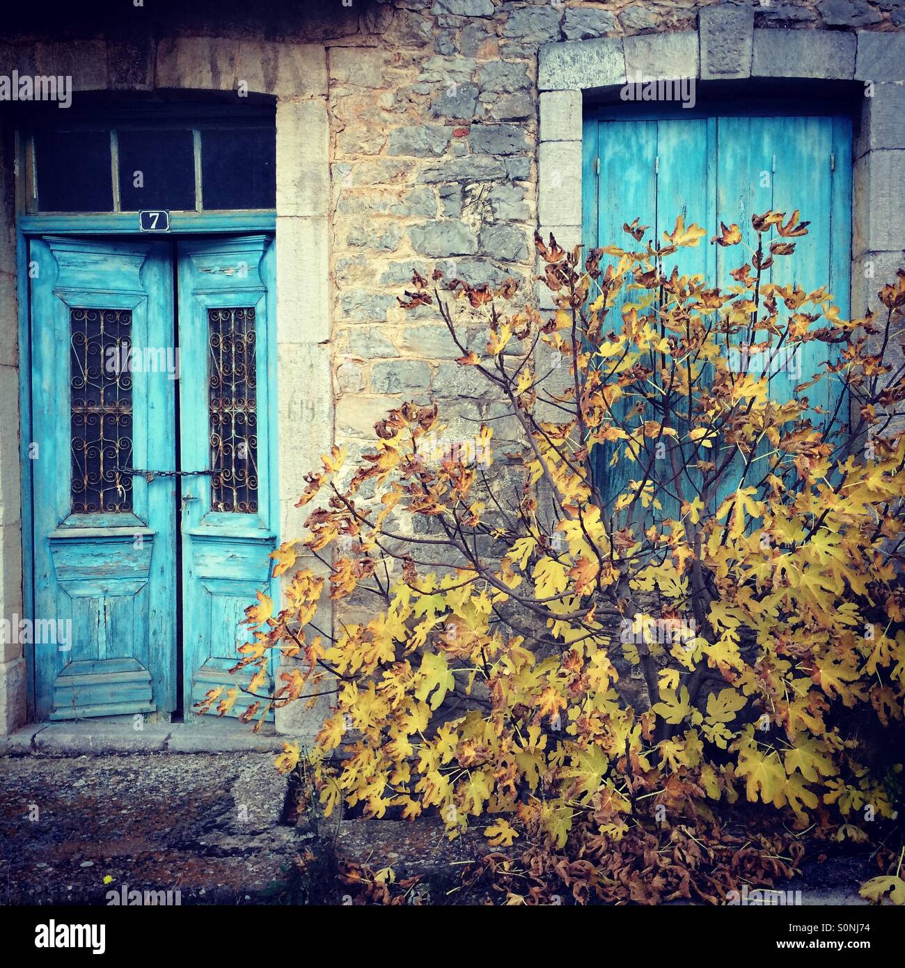 Maison en pierre ancienne et abandonnée avec double porte et fenêtre de couleur vive, dans le village pittoresque de Levidi, région d'Arcadie, Péloponnèse, Grèce. - Image de stock capturée avec un smartphone