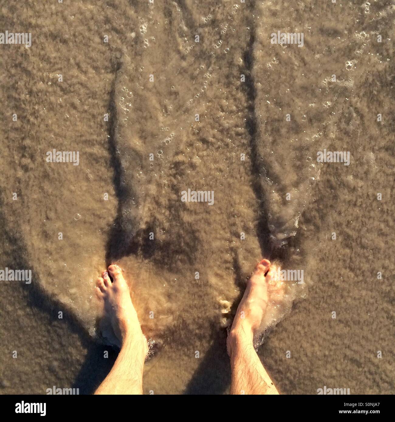 Debout sur la plage comme une vague retourne dans le golfe du Mexique. Banque D'Images