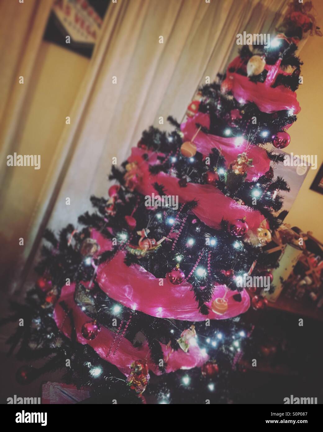 Arbre de Noël illuminé et orné de babioles et rose - Image de stock capturée avec un smartphone