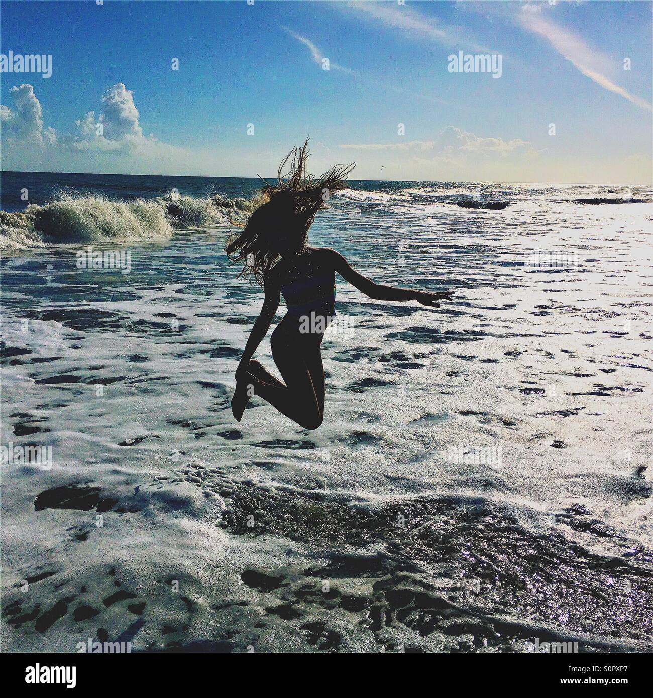 Fille sautant dans les vagues de l'océan Banque D'Images