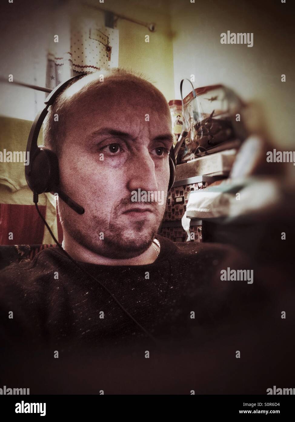 Un homme assis et portant un casque de l'ordinateur avec casque et microphone. - Image de stock capturée avec un smartphone