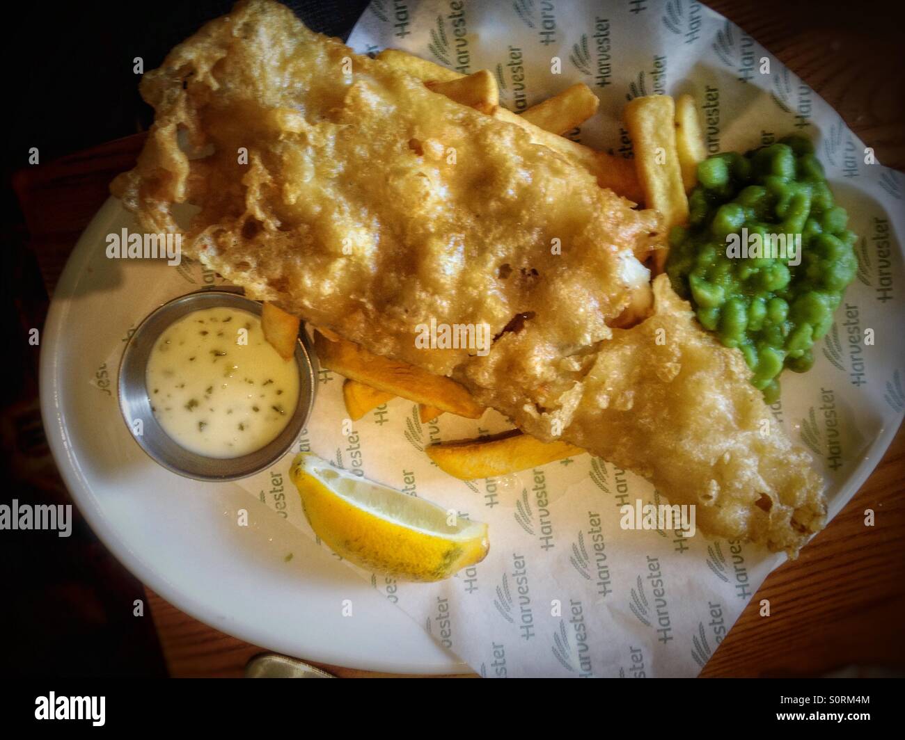 Une portion de poisson, de chips et de petits pois de l'échelon local restaurant Harvester. - Image de stock capturée avec un smartphone