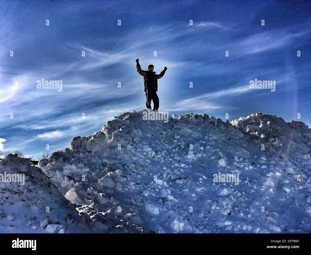 Un jeune garçon sur le dessus d'un monticule de neige massive Banque D'Images