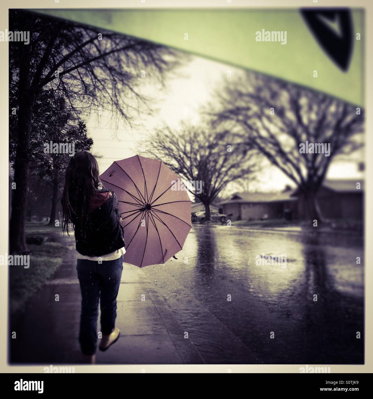 Un jeune de 12 ans fille joue dehors sous la pluie. Banque D'Images