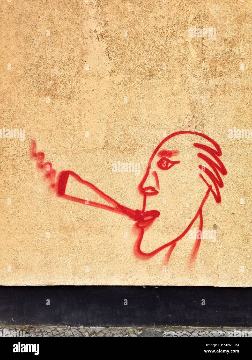 Le Graffiti d'un homme qui fume une cigarette ou un joint sur un mur jaune Banque D'Images