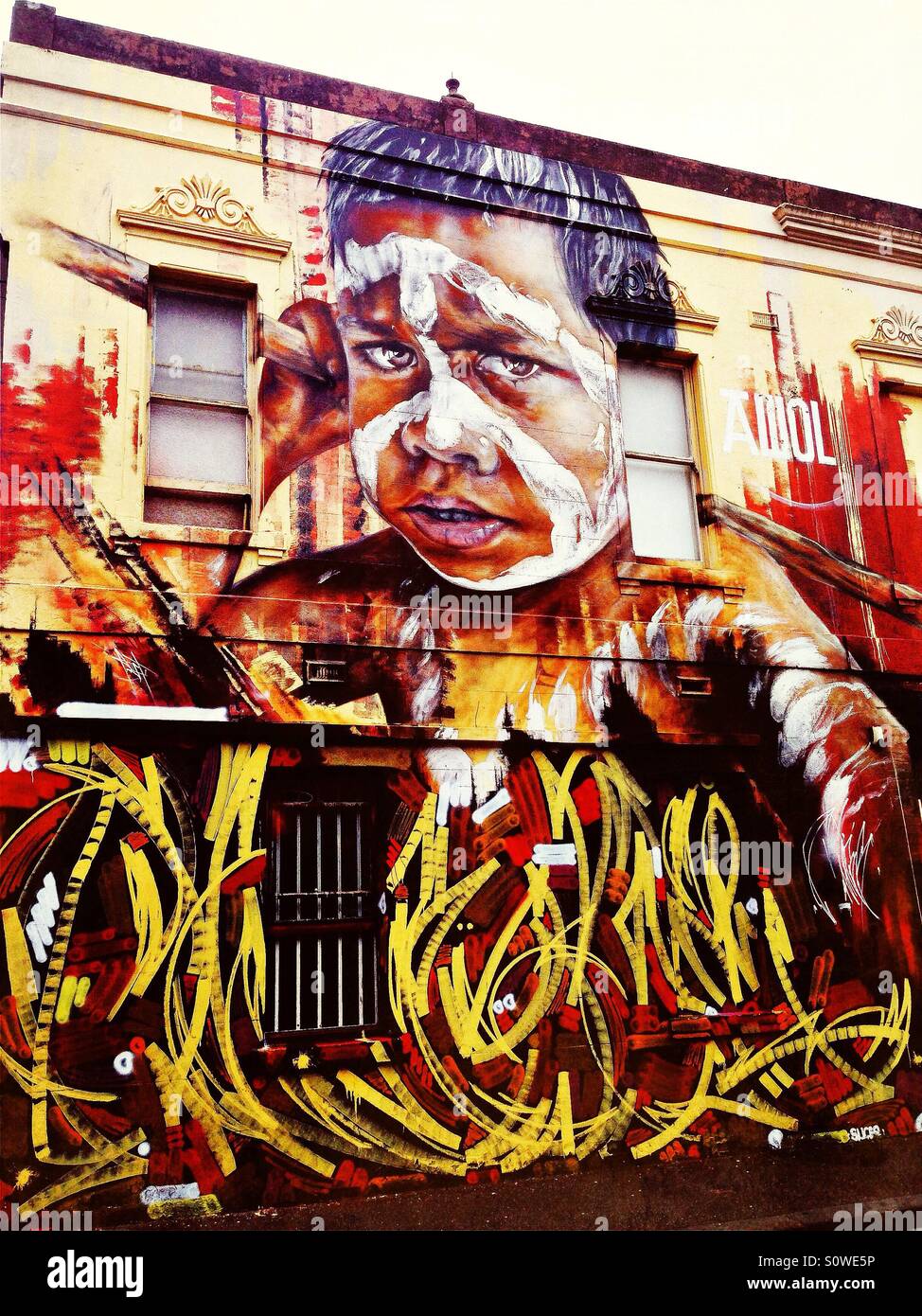 L'art de rue sur la construction de l'enfant autochtone australienne avec la peinture pour le visage à Melbourne Banque D'Images