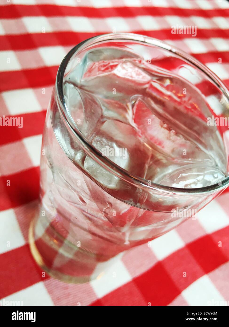 Verre à eau sur la glace sur une nappe à carreaux rouges et blancs. - Image de stock capturée avec un smartphone
