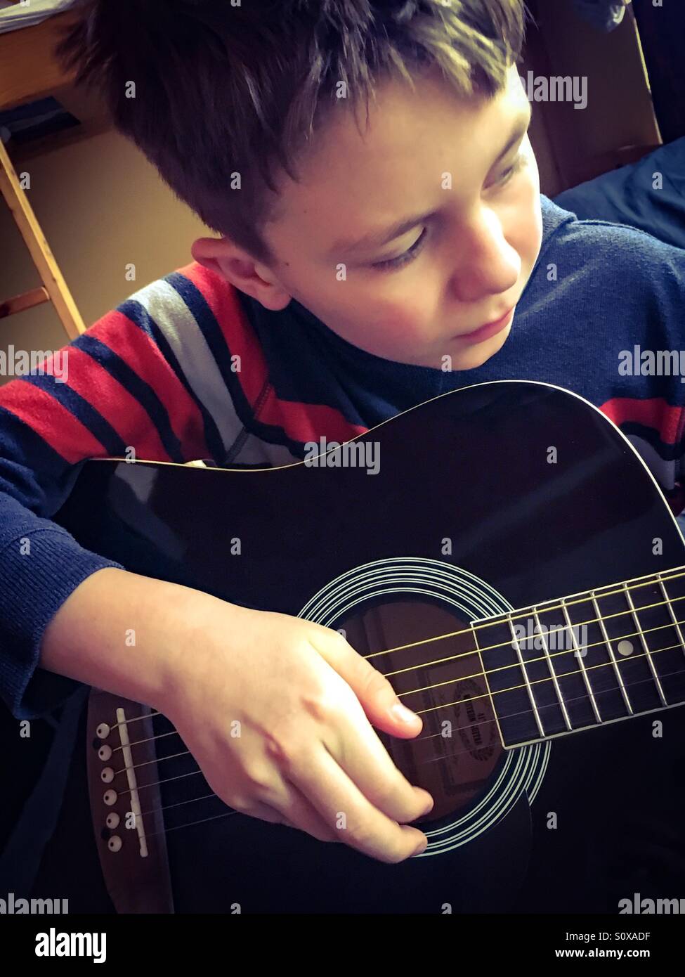 Garçon de 11 ans jouant de sa guitare dans la matinée Banque D'Images