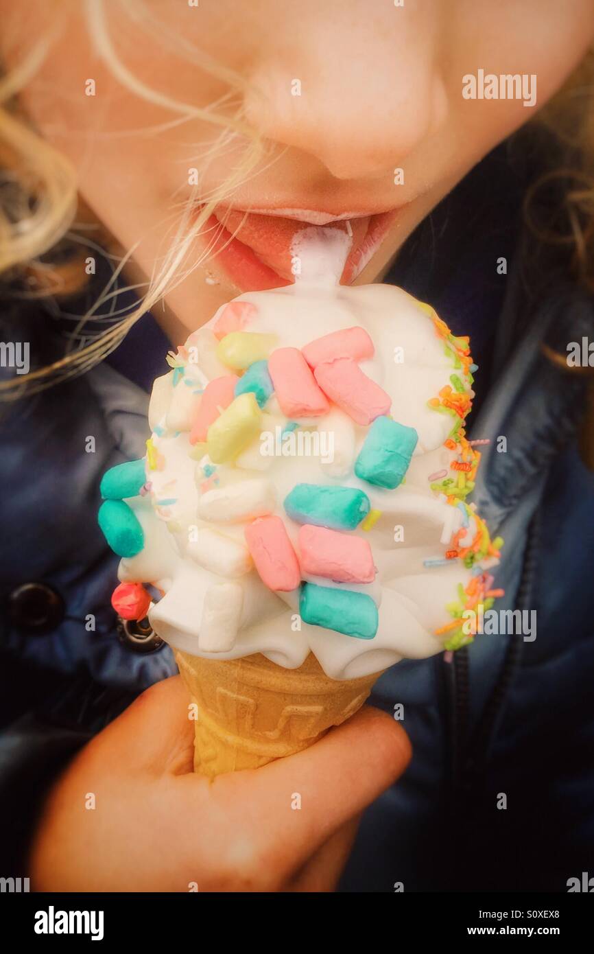 Jeune fille de lécher la crème glacée couvert de guimauve Banque D'Images