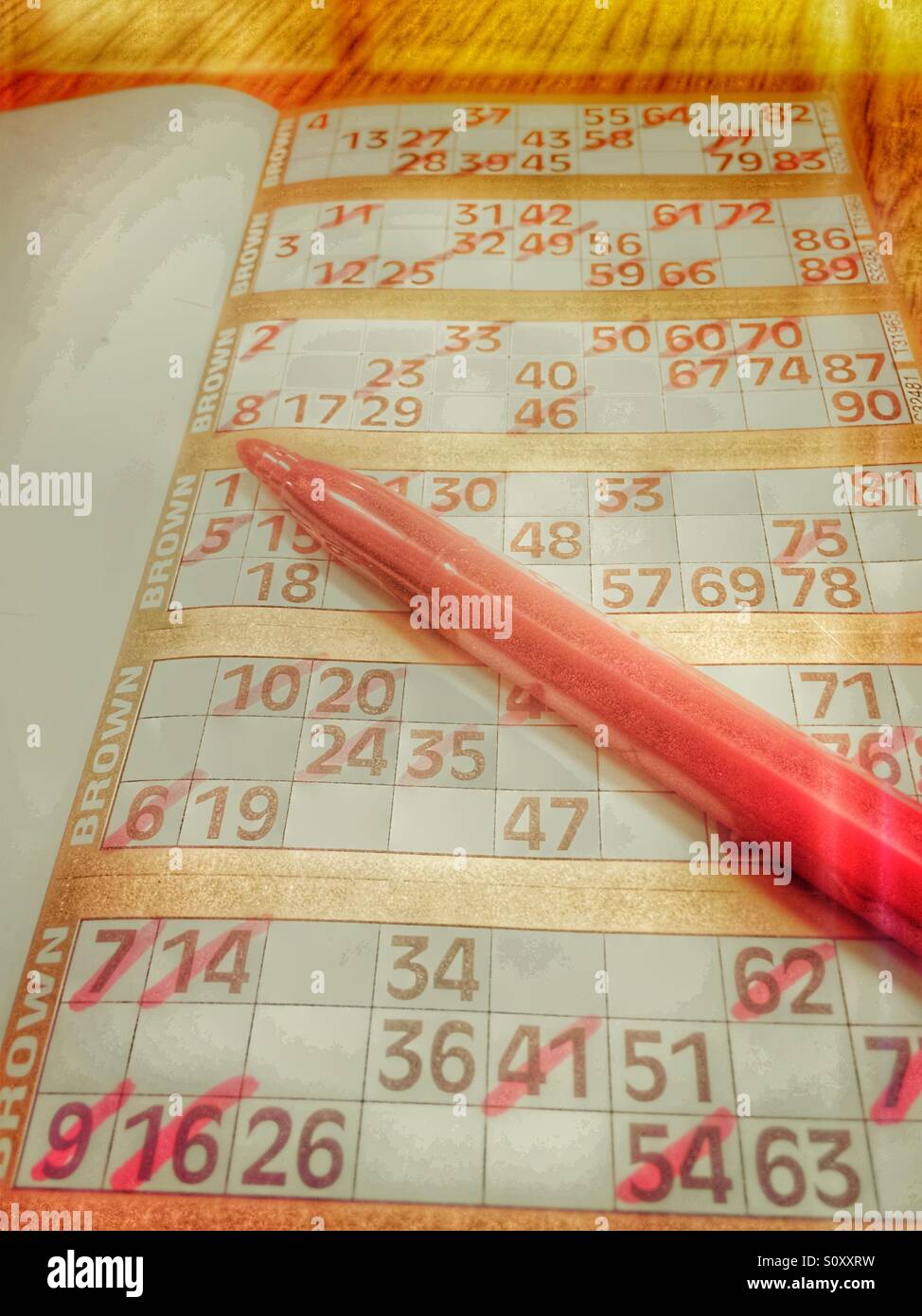 Livres de bingo et stylo montrant biffées de nombres. Banque D'Images