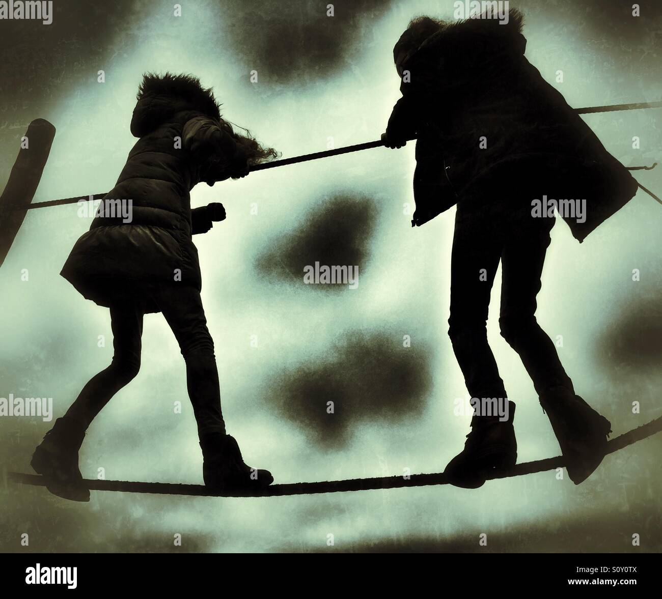Deux jeunes filles en silhouette en équilibre sur corde à pied Banque D'Images