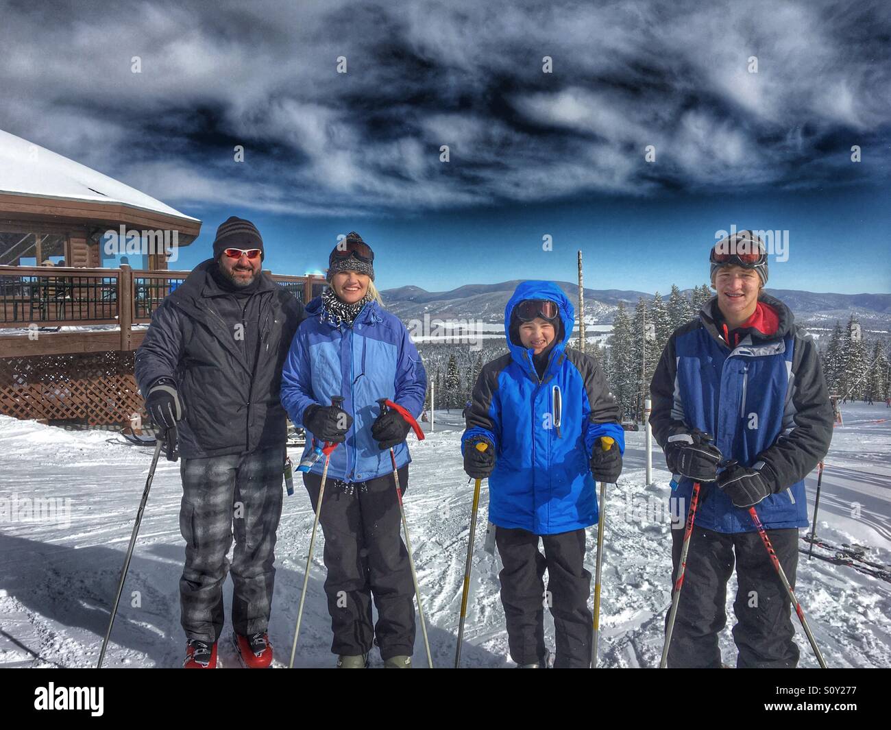 Famille de quatre, le ski de neige avec un ciel bleu en arrière-plan. Banque D'Images