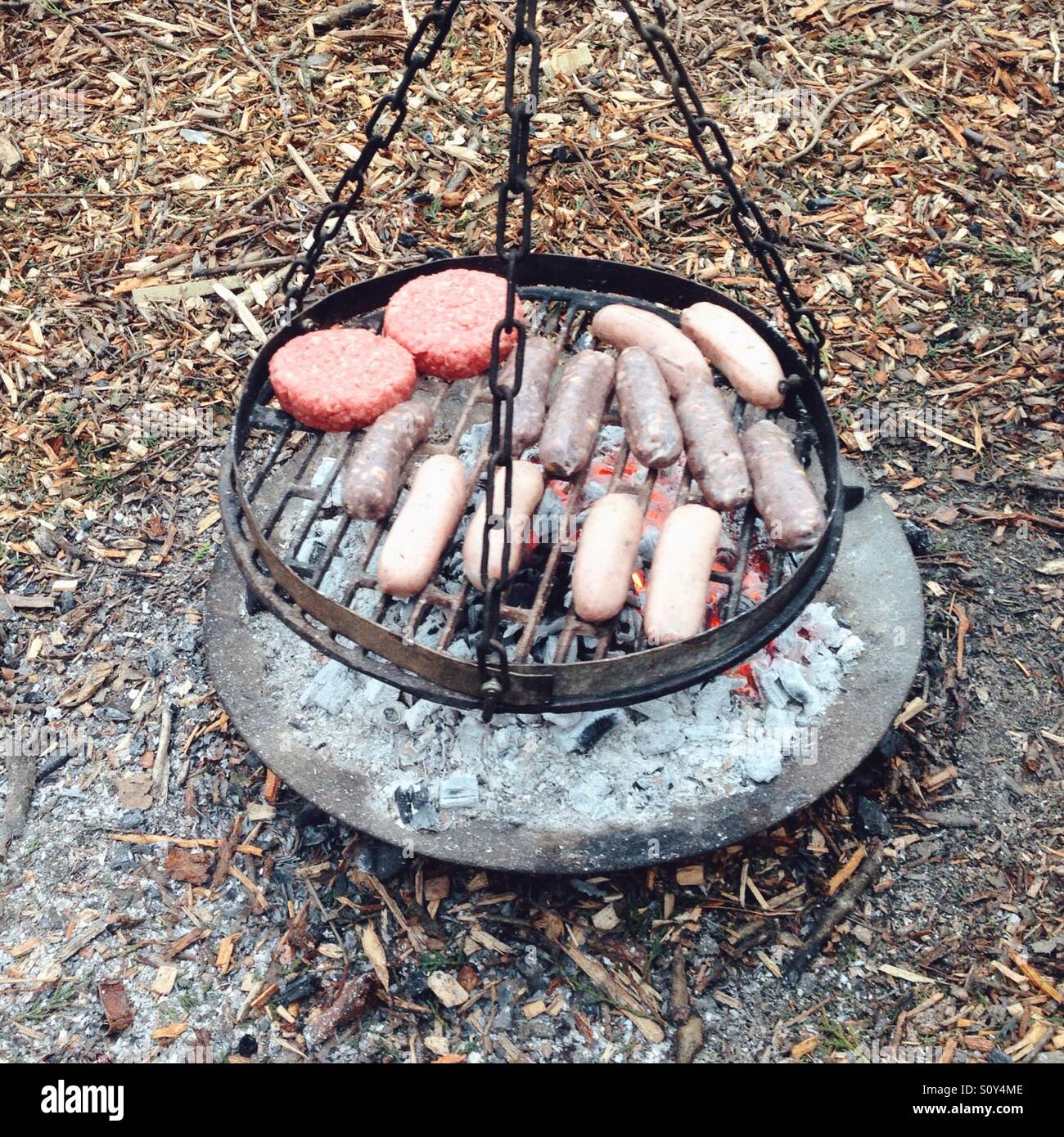 Saucisses et hamburgers cuisiner sur un barbecue au charbon. - Image de stock capturée avec un smartphone