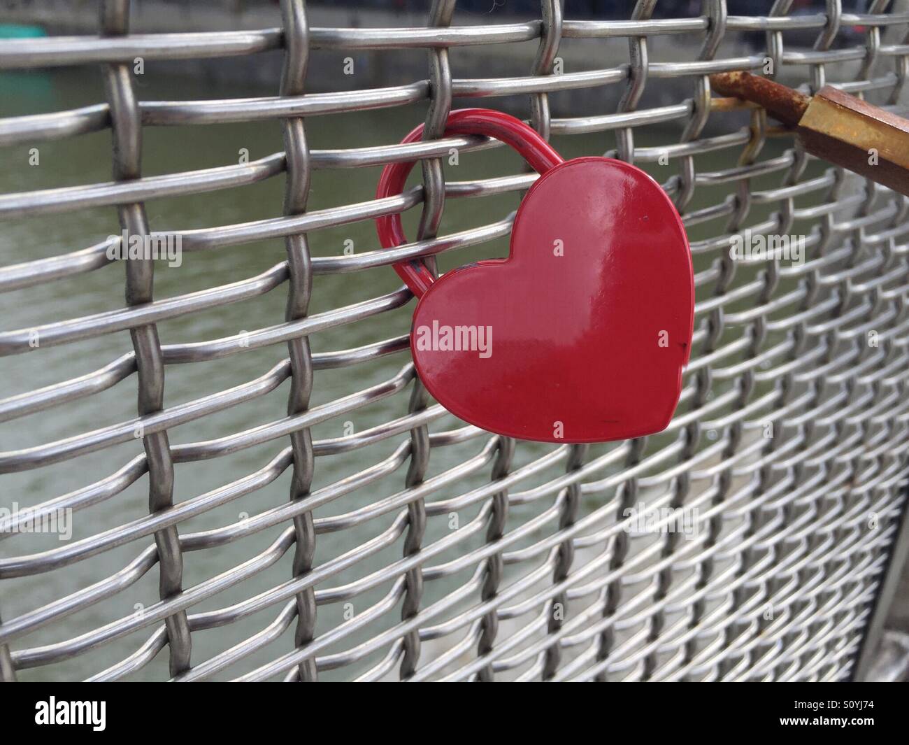 Un cadenas en forme de coeur rouge sur un treillis métallique. Vu sur une passerelle à Bristol. Symbolique de l'amour, le mariage et les relations. En particulier dans un environnement urbain où les gestes romantiques sont rares. Banque D'Images