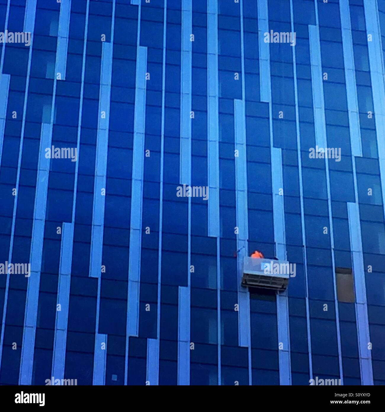 Travailleur du bâtiment l'entretien travail par rapport à la façade de verre gratte-ciel Banque D'Images