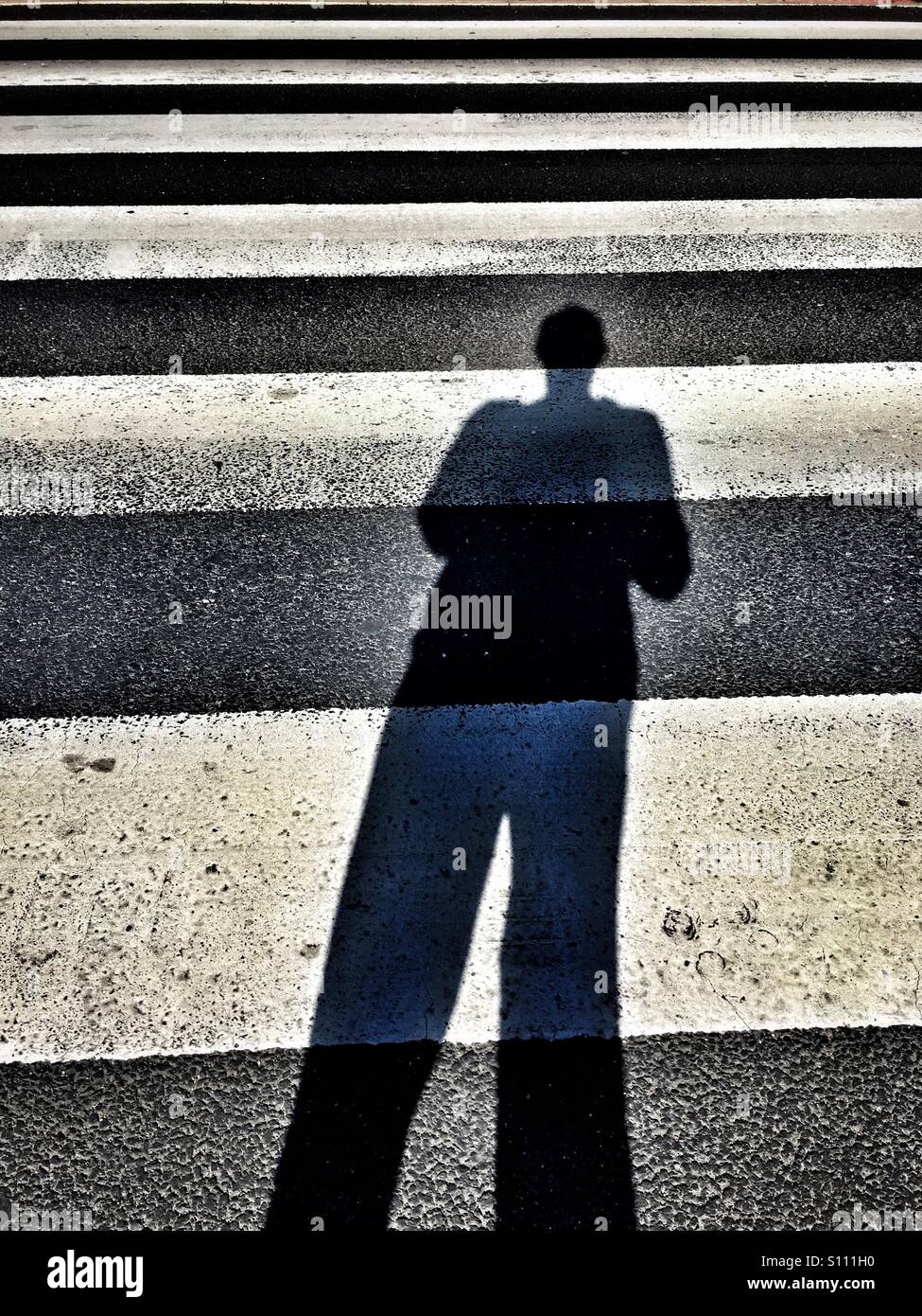 Ombre de l'homme à travers zebra crossing Banque D'Images