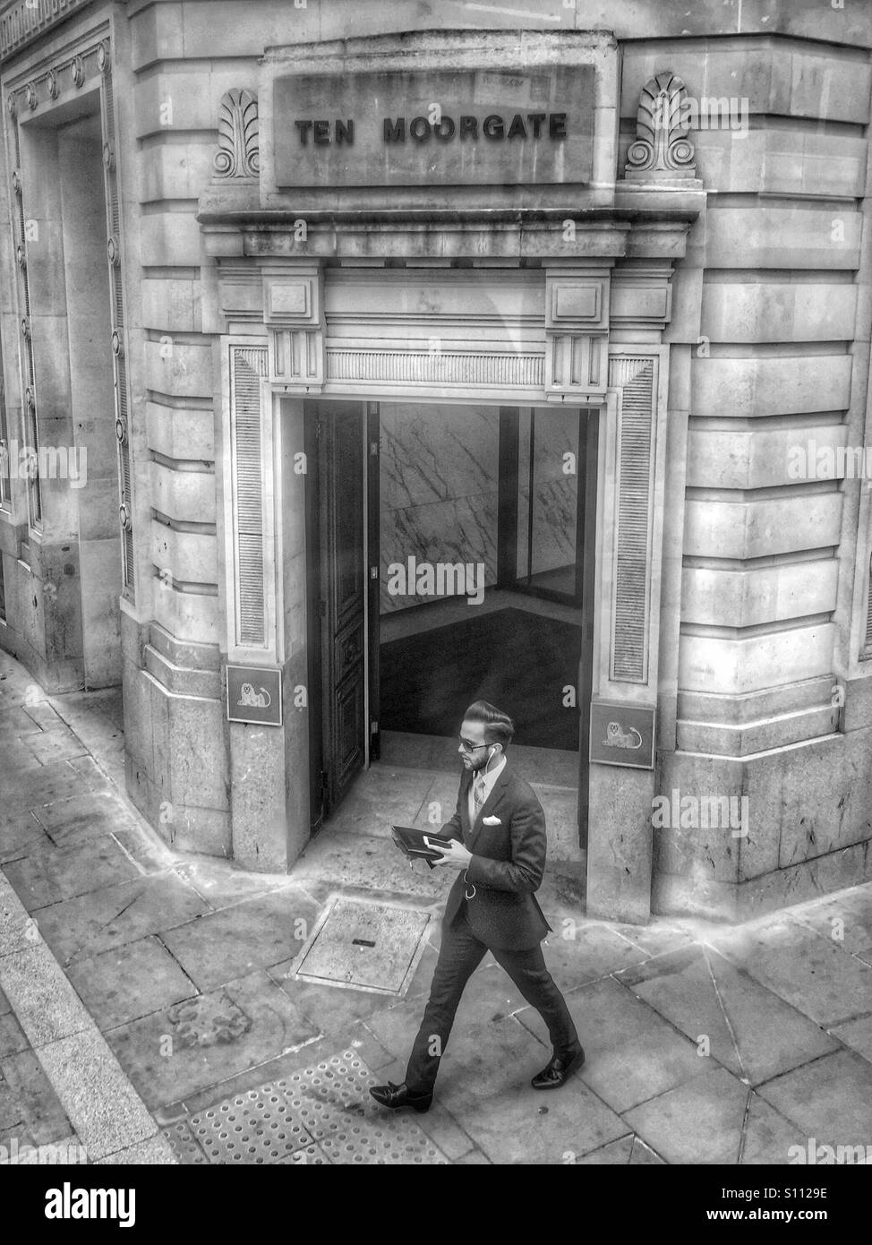 Homme en costume, marchant et parlant sur téléphone mobile. Moorgate. Londres, R.-U. Banque D'Images