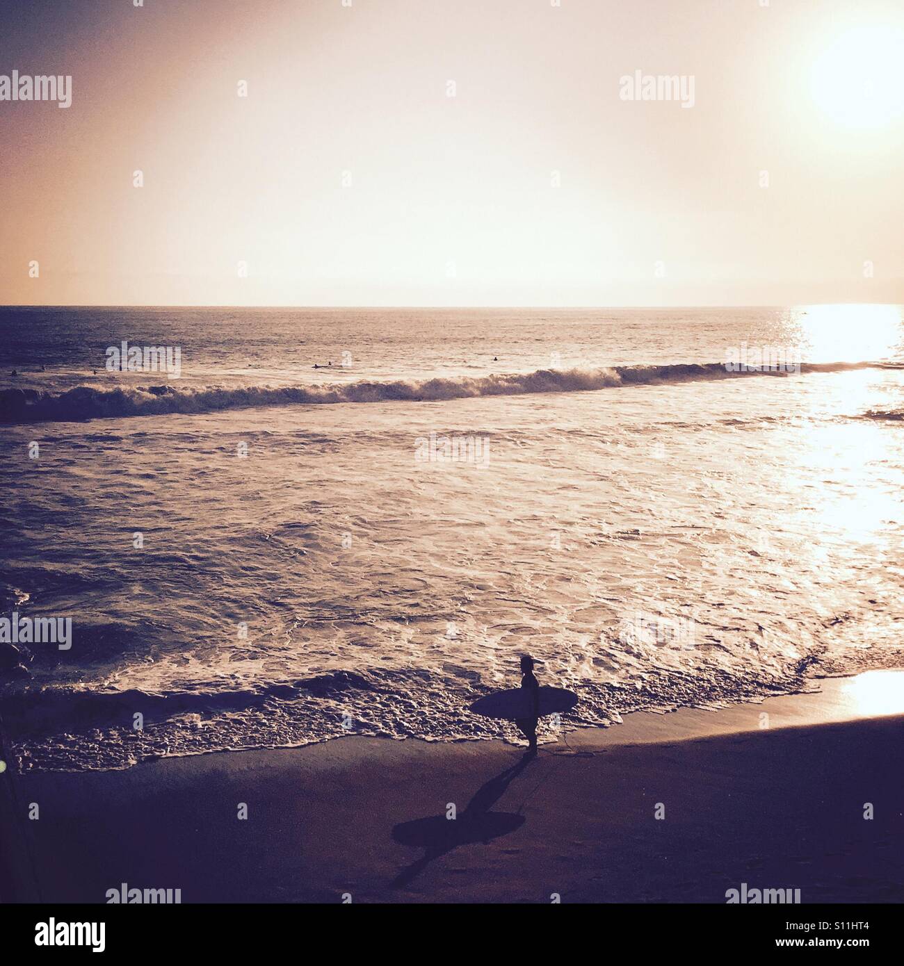 Un surfeur marchant sur la plage de vagues. Manhattan Beach, Californie, USA. - Image de stock capturée avec un smartphone