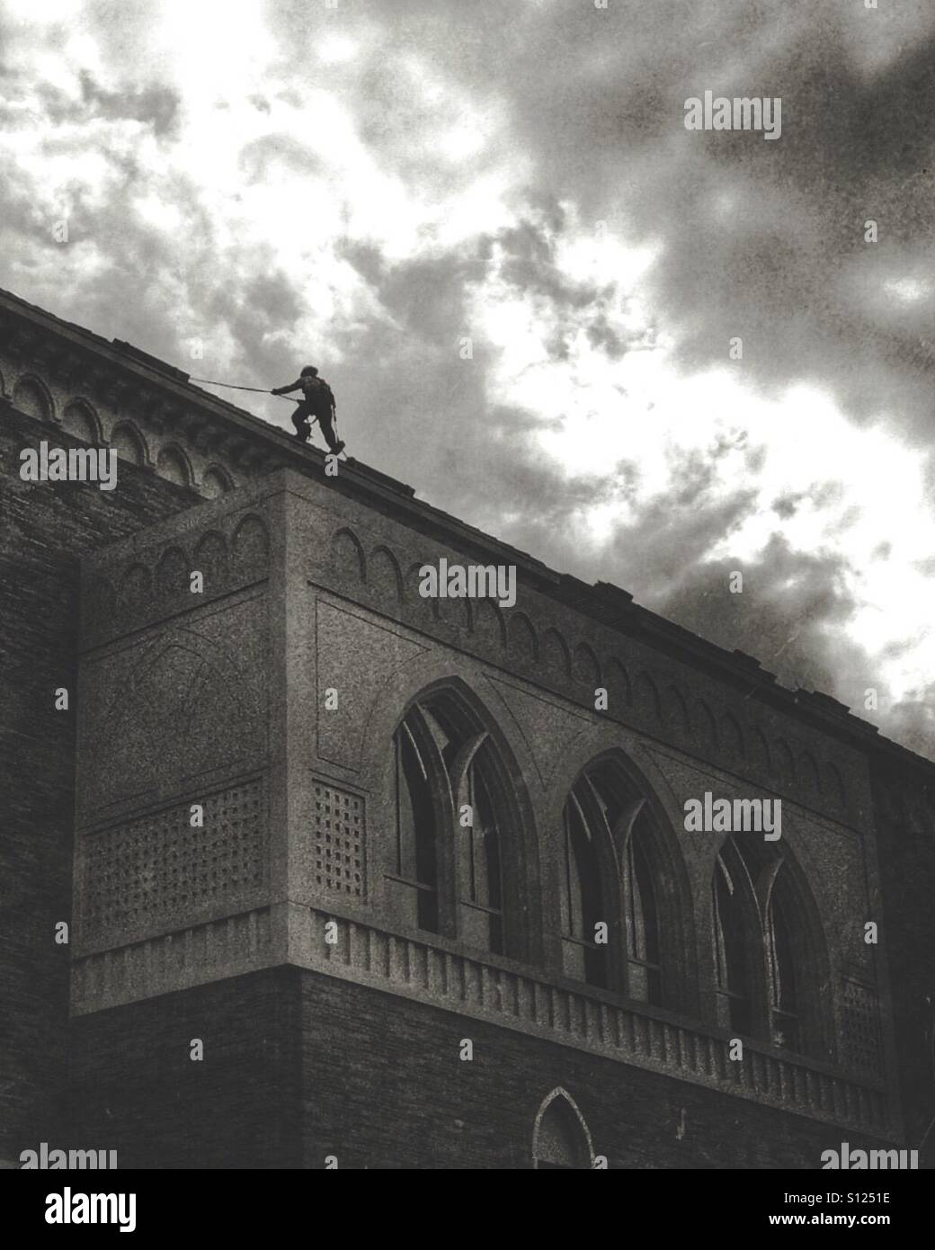 Un travailleur de la construction grimpe le toit d'un bâtiment Banque D'Images