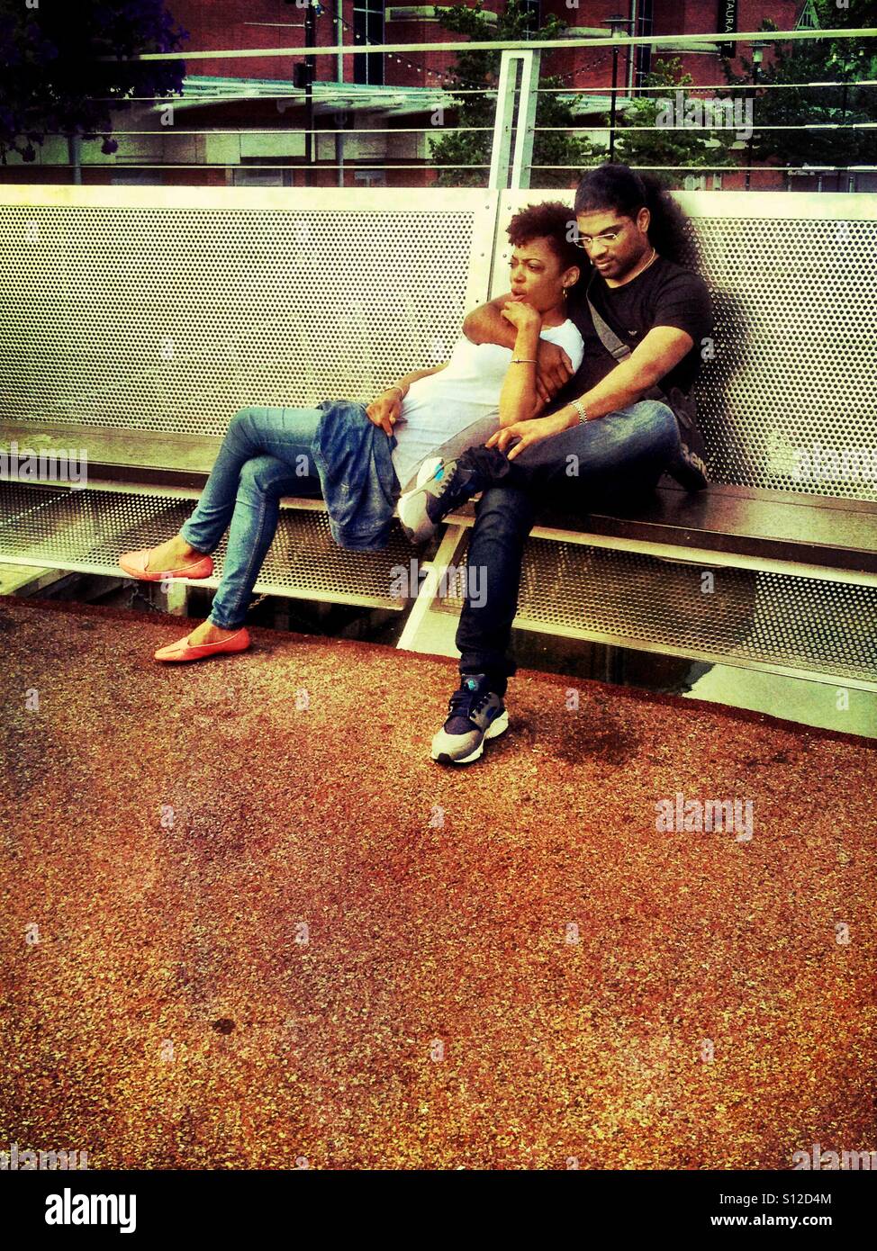 Un couple s'asseoir ensemble sur un banc et se collent. - Image de stock capturée avec un smartphone