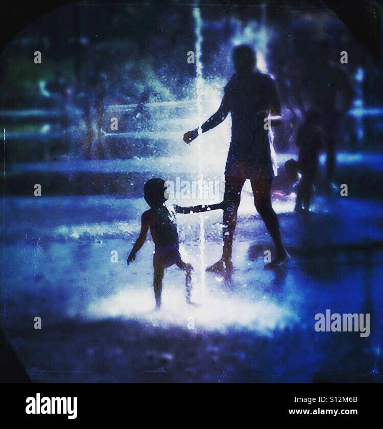 Père et fils jouant dans une fontaine dans la chaleur de l'été - Image de stock capturée avec un smartphone