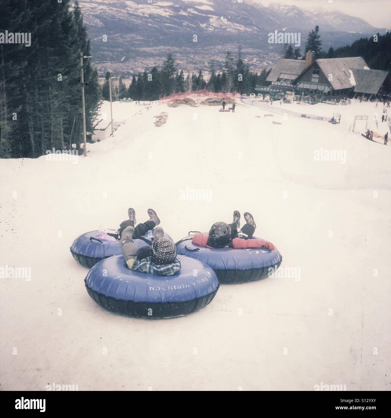 Trois enfants commencent leur glisser sur une colline sur innertubes. - Image de stock capturée avec un smartphone