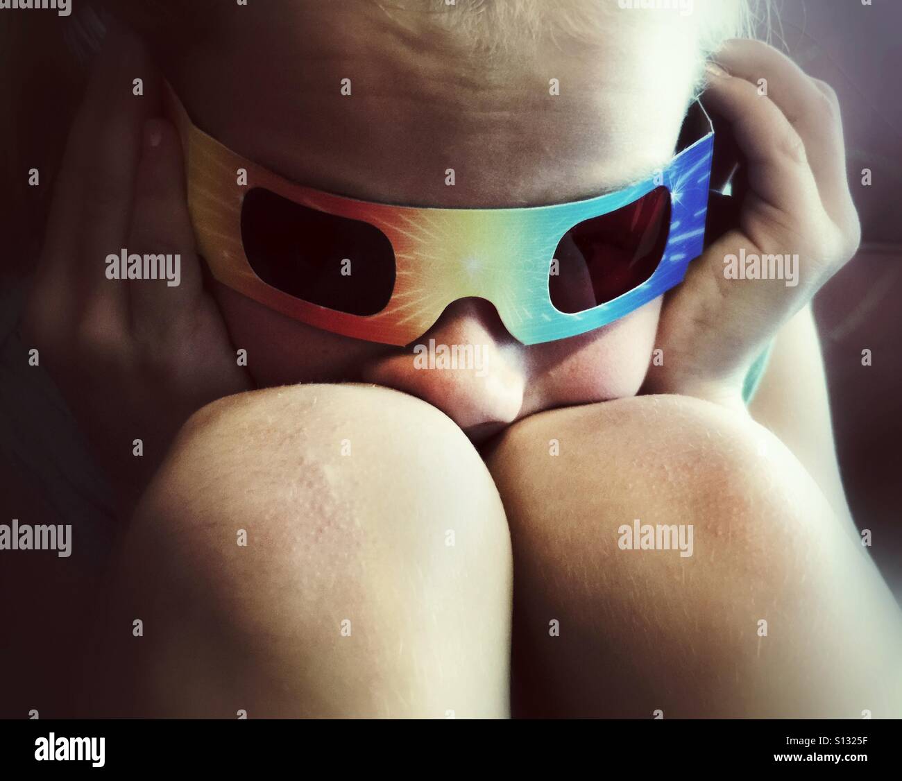 Un enfant portant des lunettes 3D a son nez écrasée entre ses genoux. - Image de stock capturée avec un smartphone
