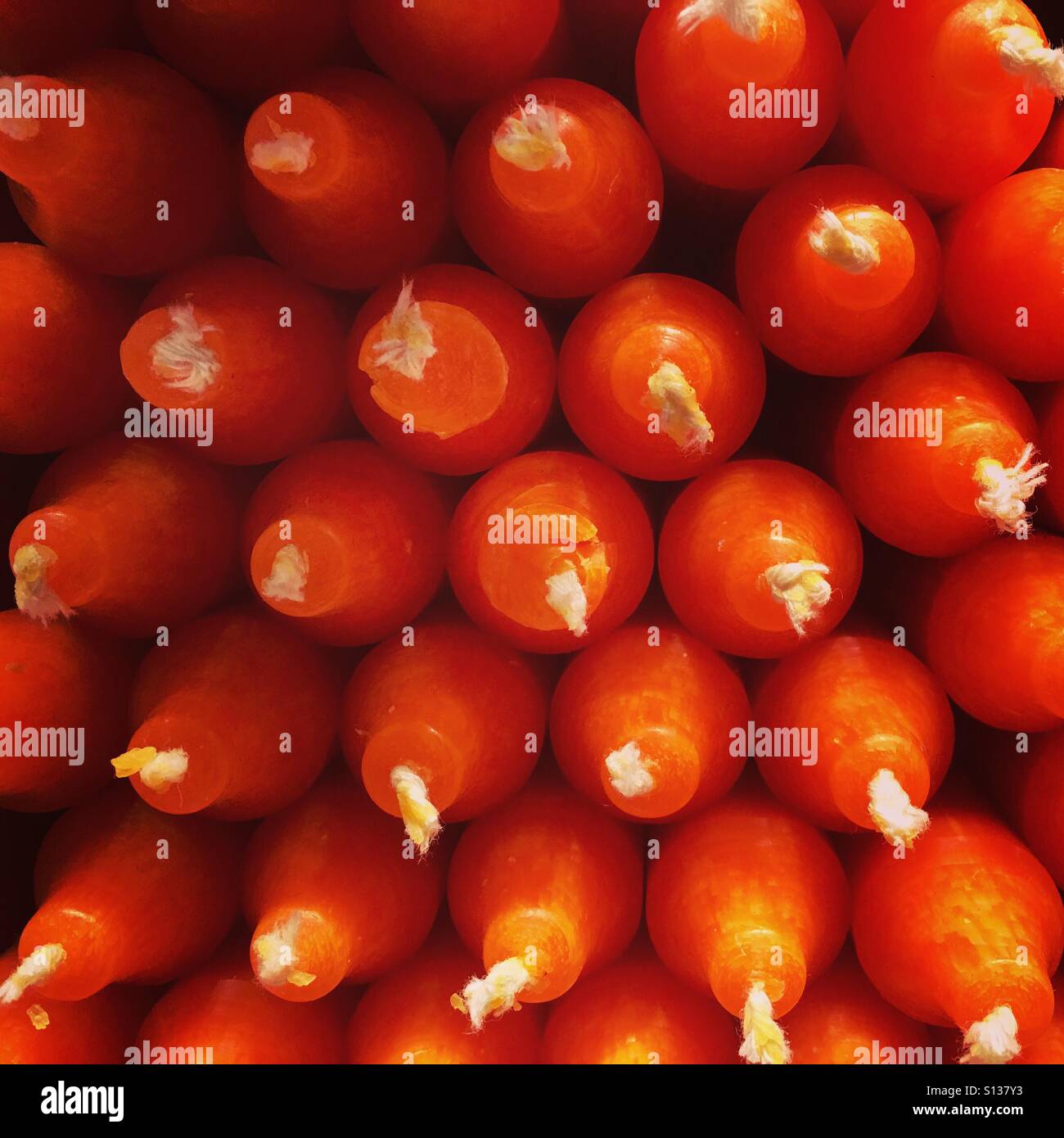 Close-up d'un tas de bougies orange empilés. Banque D'Images