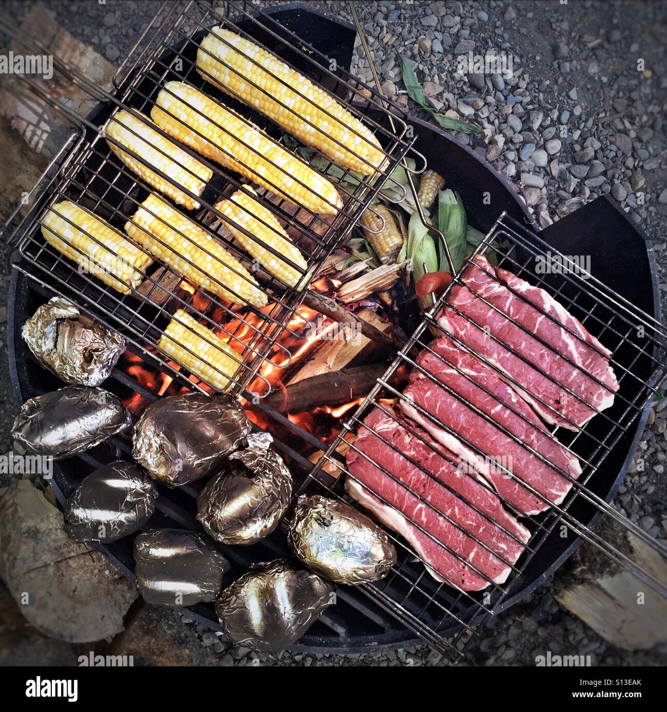 Un grand repas est préparé sur un feu de camp. Banque D'Images