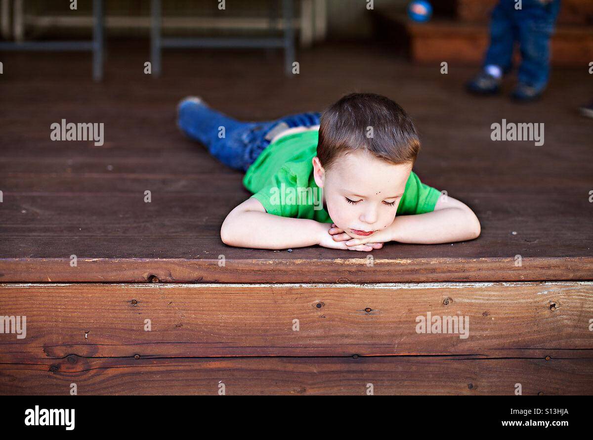 Sad boy sur le porche de cabin in woods Banque D'Images
