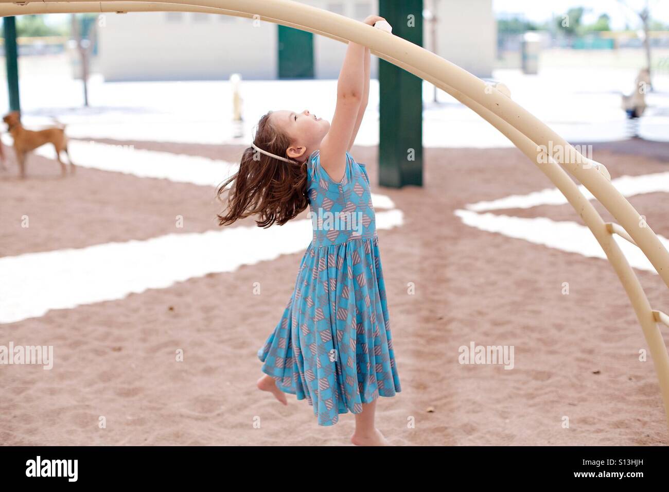 Girl hanging from monkey bars at park Banque D'Images