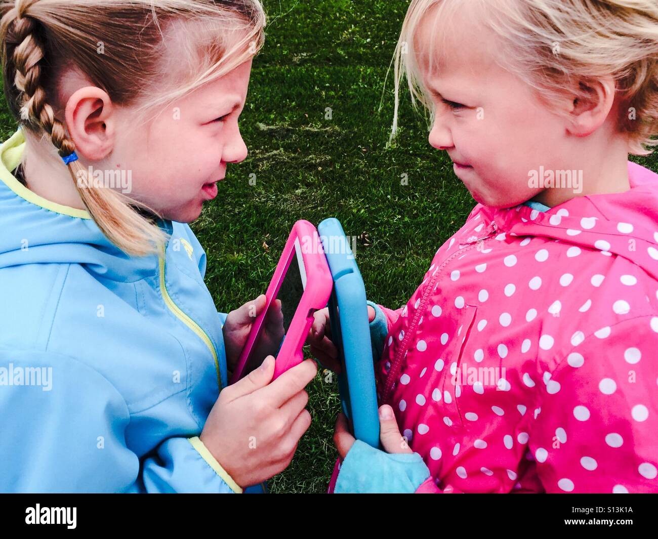 Deux filles avec les tablettes s'affrontent sur un jeu. - Image de stock capturée avec un smartphone