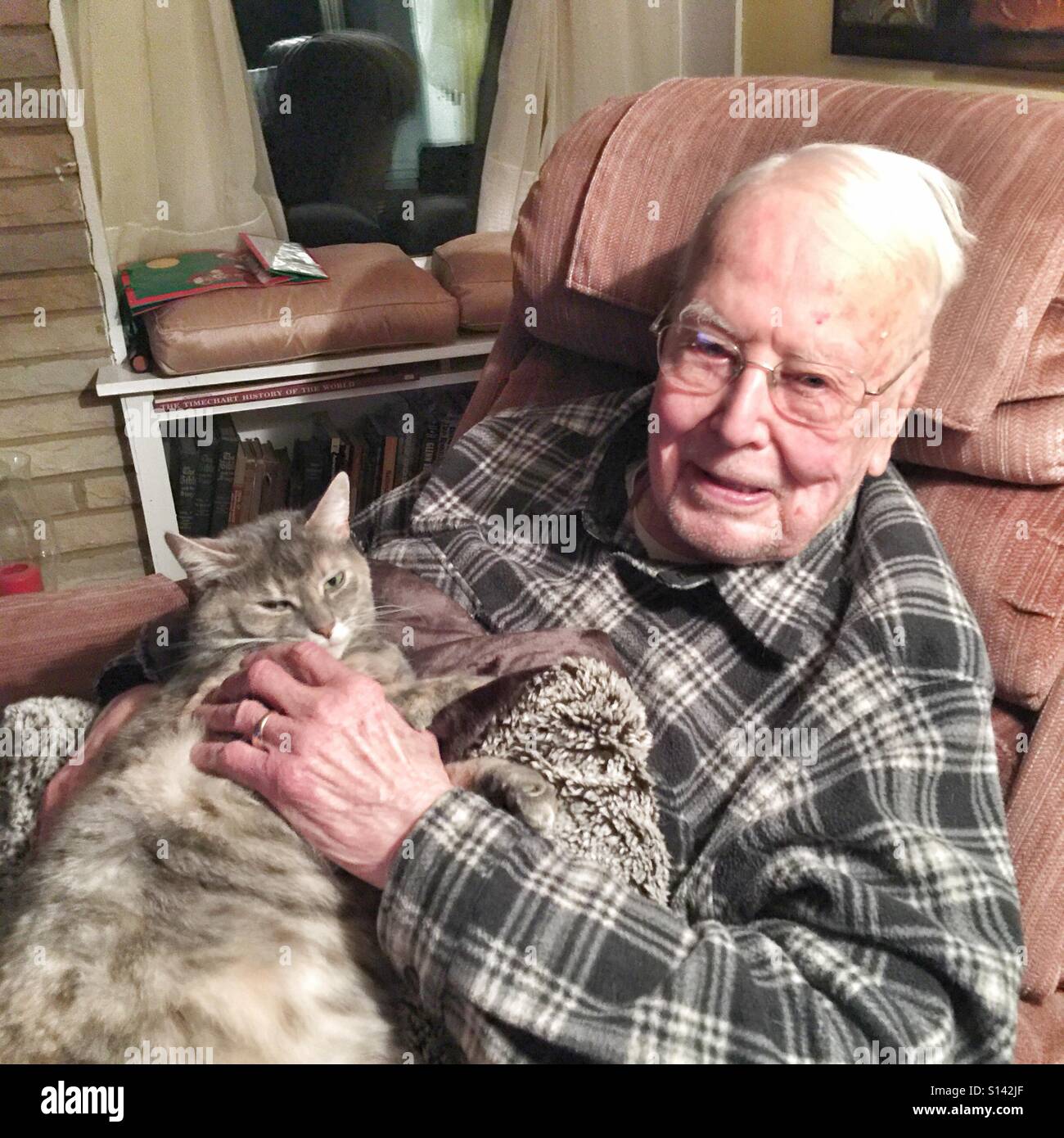 96-year-old gentleman posant avec son ami félin sur ses genoux. Banque D'Images